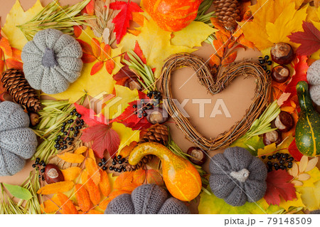 Autumn natural organic background. Vibrant color red orange yellow foliage leaves on beige background and heart shaped wreath with copy space, seasonal love, Thanksgiving greeting card Autumn natural organic background. Vibrant color red orange yellow foliage leaves on beige background and heart shaped wreath with copy space, seasonal love, Thanksgiving greeting card 79148509