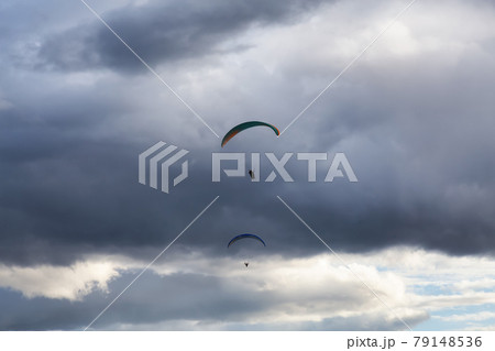Adventurous Man Flying on a Paraglider around the mountains. 79148536