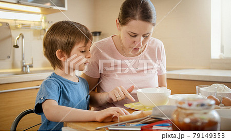 Young mother checking recipe on smartphone while baking pie or cake with her little son. Children cooking with parents, little chef, family having time together, domestic kitchen. Young mother checking recipe on smartphone while baking pie or cake with her little son. Children cooking with parents, little chef, family having time together, domestic kitchen. 79149353