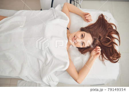 Attractive woman with dark hair covered with white towel Attractive woman with dark hair covered with white towel 79149354