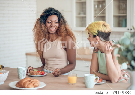Laughing dark-skinned woman and girlfriend during breakfast 79149830