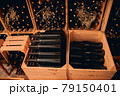Glass bottles of wine stored in wooden crates and wine racks 79150401