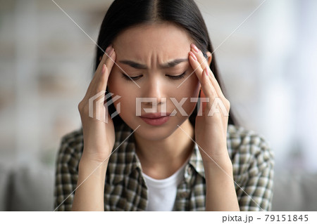 Closeup of young asian woman having headache, touching her temples Closeup of young asian woman having headache, touching her temples 79151845