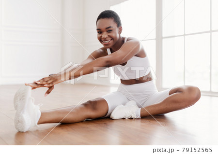 Cheerful Black Woman In Sportswear Stretching Leg On Floor Cheerful Black Woman In Sportswear Stretching Leg On Floor 79152565