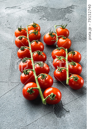 Ripe branch of cherry tomatoes, on gray stone background Ripe branch of cherry tomatoes, on gray stone background 79152740