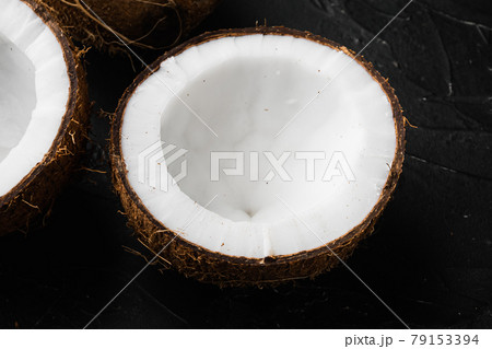 Coconut halves, coconut pieces, on black dark stone table background Coconut halves, coconut pieces, on black dark stone table background 79153394