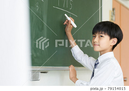 黒板に字を書く少年の写真素材 黒板に字を書く少年の写真素材