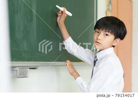 黒板に字を書く少年の写真素材