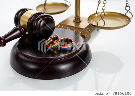 Two gold wedding rings with lgbt rainbow colours. Homosexual marriage. Lgbt rights and law. 79156100