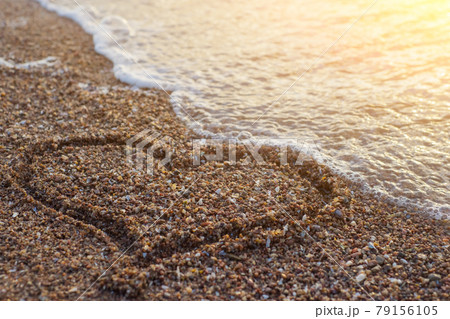 Heart on a sand of beach with wave on background. Heart on a sand of beach with wave on background. 79156105