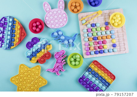 Set of trendy colorful fidget toys pop it and wooden clip beads board game on blue background.  79157207