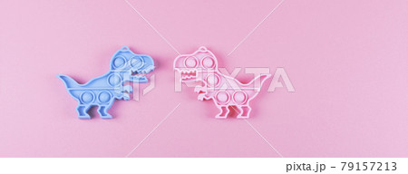 Banner. Two silicone fidget toys pop it in shape of dinosaur on the pink background. 79157213