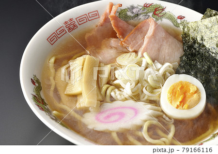 チャーシューなど色々な具材が乗っている屋台で食べるような昔ながらの熱々醤油ラーメンを黒背景で撮影 79166116