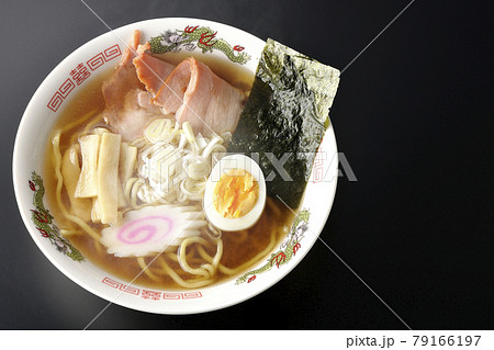 チャーシューなど色々な具材が乗っている屋台で食べるような昔ながらの熱々醤油ラーメンを黒背景で俯瞰撮影 79166197