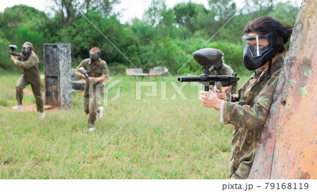 Group of friends paintball players of opposite teams in shootout in forest 79168119