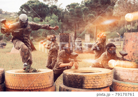 Two active opposing teams with guns playing paintball Two active opposing teams with guns playing paintball 79170761