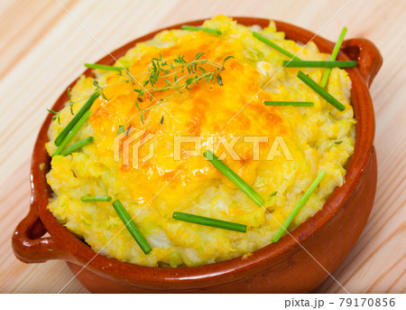 Scottish cuisine. Mix of mashed potatoes, fried cabbage, onions and cheddar cheese served in clayware with greens. 79170856