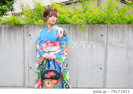 木々とコンクリートの壁の前でこちらを見る青い振袖の女性 木々とコンクリートの壁の前でこちらを見る青い振袖の女性 79171851