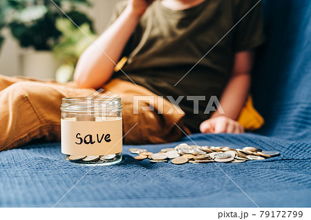 Close up of Little child kid boy hands grabbing and putting stack coins in to glass jar with save label. Donation, saving money, charity, family finance plan concept Close up of Little child kid boy hands grabbing and putting stack coins in to glass jar with save label. Donation, saving money, charity, family finance plan concept 79172799