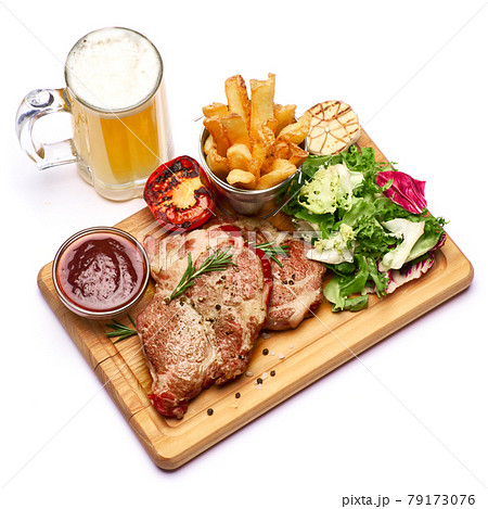 Grilled roated beef steaks, potato, sauce and salad on wooden cutting board 79173076