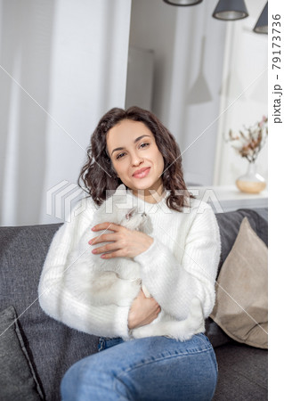 Cute young woman sitting on the sofa and hugging her cat Cute young woman sitting on the sofa and hugging her cat 79173736