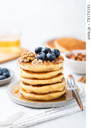 Stack of pancakes served with syrup, blueberries and walnuts 79174191