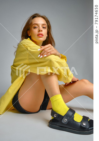 Stylish young girl sitting on grey studio background Stylish young girl sitting on grey studio background 79174650