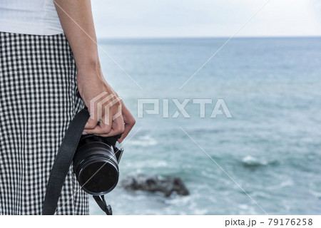 Close-up of a young female tourist holding a camera on the Kenting coast of Pingtung, Taiwan Close-up of a young female tourist holding a camera on the Kenting coast of Pingtung, Taiwan 79176258