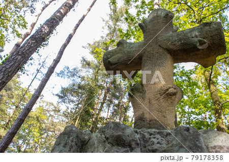 A stone Christian cross under the treetops. 79178358