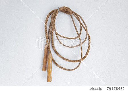 A old skipping rope hanging on a white wall. 79178482