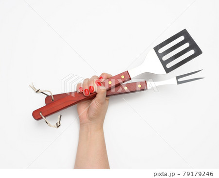 metal spatula and fork with a wooden handle for a picnic in a female hand with painted red nails on a white background metal spatula and fork with a wooden handle for a picnic in a female hand with painted red nails on a white background 79179246