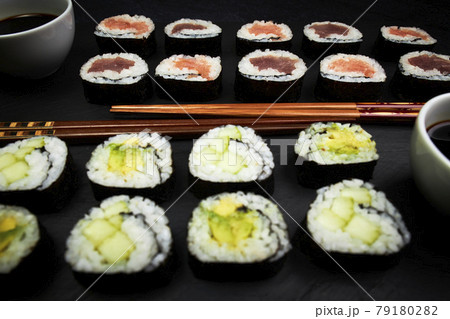 Delicious Japanese sushi next to wooden chopsticks on a black board. Delicious Japanese food Delicious Japanese sushi next to wooden chopsticks on a black board. Delicious Japanese food 79180282