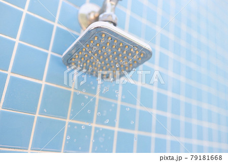 Wall mounted chrome shower on blue tiles with water drops 79181668