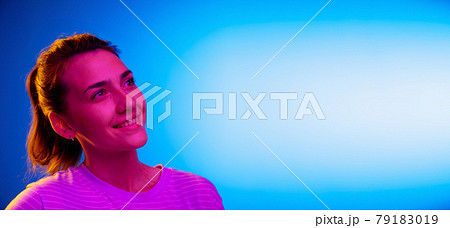 Caucasian young woman's portrait on dark studio background in neon. Concept of human emotions, facial expression. 79183019