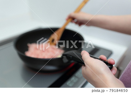 IHクッキングヒーターの上でフライパンを持って料理する主婦の女性 IHクッキングヒーターの上でフライパンを持って料理する主婦の女性 79184650