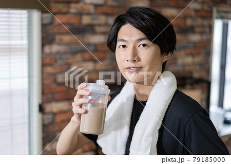 プロテインを飲む汗をかいた若い男性のポートレート 79185000