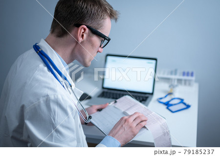 Topic of timely checking for heart disease. Heart disease myocardial infarction. Doctor analyzing electrocardiogram at the desk in hospital office. Cardiologist at work in clinic. doctor look at EKG 79185237