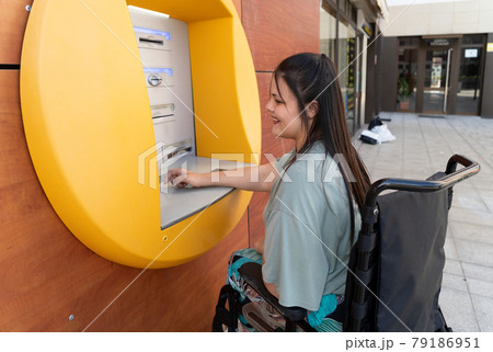 disabled young woman in wheelchair with ATM 79186951