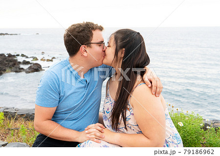 couple in love kissing each other while spending time outdoors on seaside 79186962