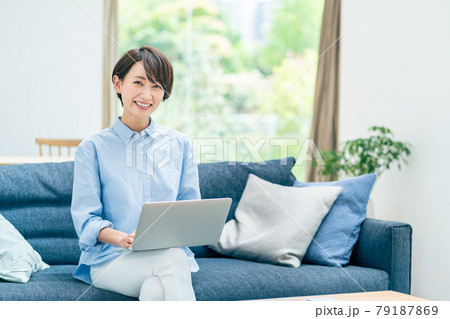 ソファーでノートPCを操作するミドル女性。 ソファーでノートPCを操作するミドル女性。 79187869