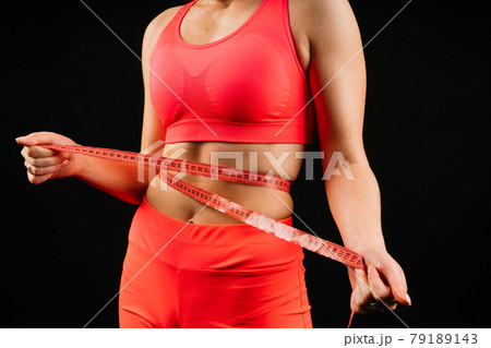Fitness woman with tape measure showing her waist on studio background Fitness woman with tape measure showing her waist on studio background 79189143