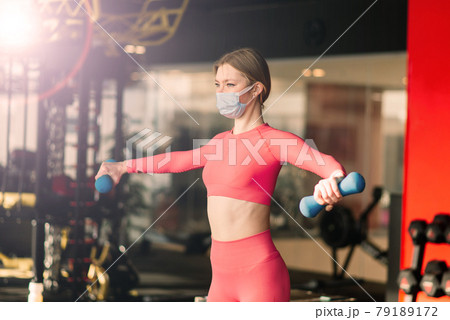 Coronavirus covid-19 prevention, fitness girl with medical mask holding a dumbbell, training circuit Coronavirus covid-19 prevention, fitness girl with medical mask holding a dumbbell, training circuit 79189172