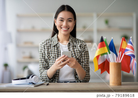 Cheerful asian young lady using smartphone, having English class Cheerful asian young lady using smartphone, having English class 79189618
