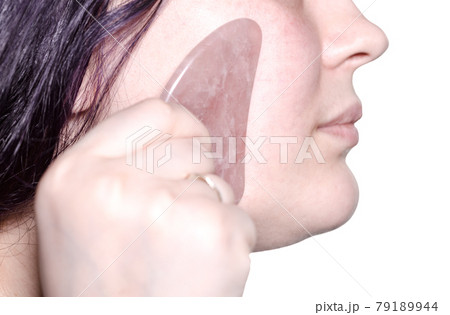massaging female face with quartz scraper isolated massaging female face with quartz scraper isolated 79189944