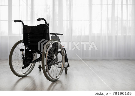 Wheelchair against window, in bright living room or hospital interior 79190139