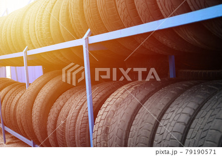 Rack with variety of car tires in automobile store. Many black tires. Tire stack background. Selective focus Rack with variety of car tires in automobile store. Many black tires. Tire stack background. Selective focus 79190571
