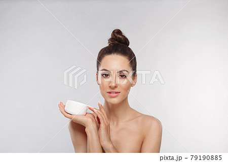 Skin care. Beauty Concept. Young woman holding cosmetic moisturizing cream. Soft skin and naked shoulders, model with light nude make-up, portrait of girl face with clean healthy skin. Dermatology 79190885