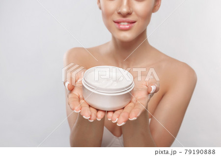 Beauty Concept. Woman holds a moisturizer cosmetic cream in her hand. Skin care. Soft skin and naked shoulders Beauty Concept. Woman holds a moisturizer cosmetic cream in her hand. Skin care. Soft skin and naked shoulders 79190888