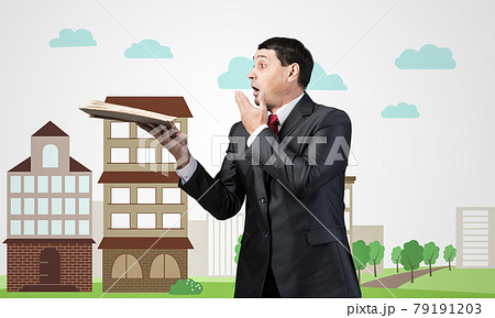 Surprised businessman holding open old book 79191203