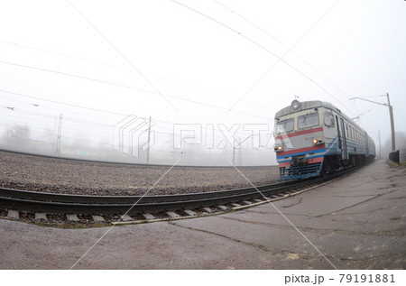 The Ukrainian suburban train rushes along the railway in a misty morning. Fisheye photo with increased distortion The Ukrainian suburban train rushes along the railway in a misty morning. Fisheye photo with increased distortion 79191881